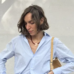 Detailansicht einer Vintage-Nautilus-Halskette mit roten Perlen an einem Model in Blau.