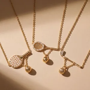 Close-up of gold-plated sports theme necklaces featuring tennis racket and golf club pendants