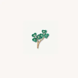 Vue rapprochée d'un délicat pendentif trèfle vert avec tige dorée et cristaux brillants
