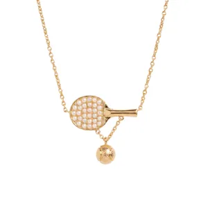 Macro view of a gold-plated table tennis paddle necklace with elegant pearl details.