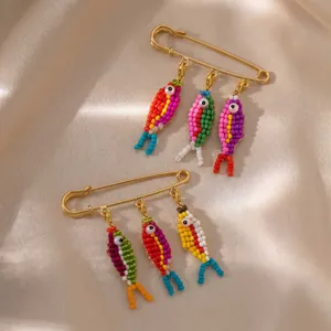 Close-up detail of colorful beaded fish charms on a gold-plated safety pin brooch