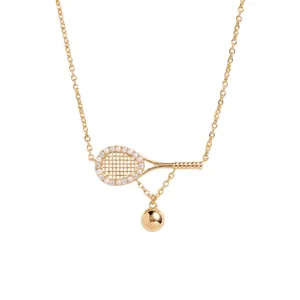 Detail view of a gold tennis racket necklace with pearl accents and a ball charm
