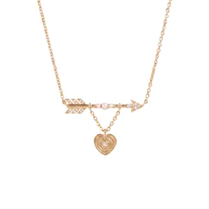 Detailed macro shot of a gold Cupid's arrow necklace with white pearls and heart pendant.