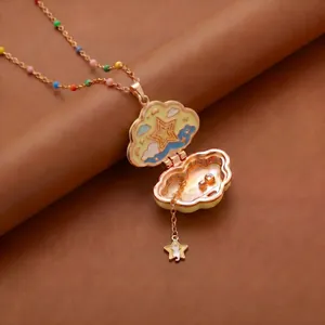 Gros plan d'un collier médaillon nuage doré avec des motifs d'étoiles et arc-en-ciel