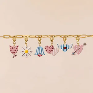 Detailed macro view of colorful acrylic printed charms attached to a gold chain necklace.