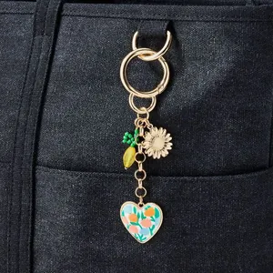 Detailansicht eines vergoldeten Taschenanhängers mit Blumenherz auf Denim