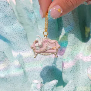 Primo piano dettagliato di un ciondolo a forma di divano con cigno rosa e dettagli dorati.