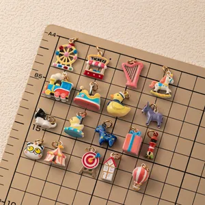 Close-up of sixteen colorful enamel jewelry charms arranged on a grid measuring mat