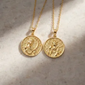 Two exquisite gold goddess coin pendant necklaces displayed on a natural stone background