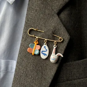 Detailed view of stainless steel safety pin brooch with rabbit and butterfly charms