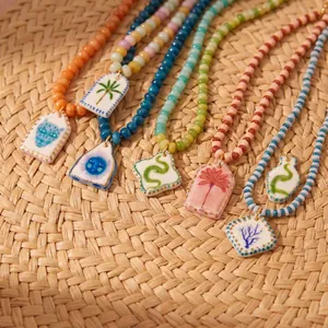 Detalle de collares de cuentas coloridas con colgantes tropicales sobre esterilla