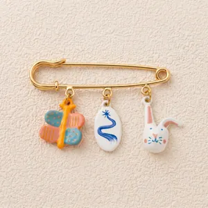 Detailed view of 18K gold-plated safety pin brooch with rabbit and butterfly charms