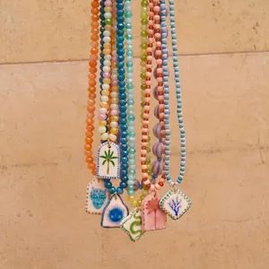 Detalle de collares de cuentas coloridas con colgantes de cerámica pintados a mano únicos.