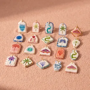 Colección de colgantes cerámicos únicos con estampados tropicales sobre fondo de arena.