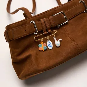 Detail of cute enamel butterfly and rabbit charms on a 18K gold plated safety pin