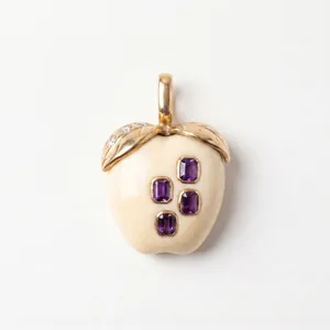 Vue détaillée d'un pendentif pomme crème orné de pierres violettes.