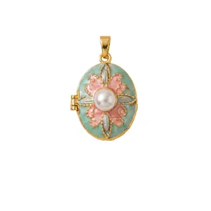 Vintage gold enamel flower locket pendant with pearl center on white background.