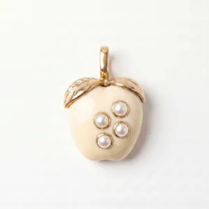 Gros plan d'un pendentif en forme de fruit avec perles incrustées et bélière dorée.