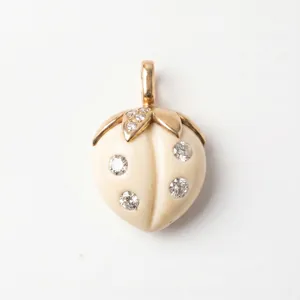 Détail du pendentif fraise crème avec des feuilles dorées et pierres