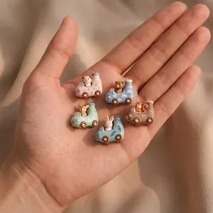 Close-up of five colorful cartoon animal car charms with intricate patterns held in hand