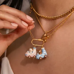 Detailed close-up of colorful enamel bear and pig car pendants on layered gold necklaces.