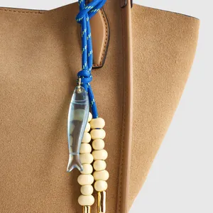 Macro view of a blue braided rope bag charm with a translucent fish pendant and beads