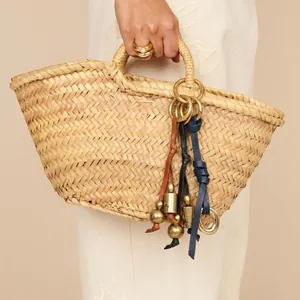 Close-up of vintage leather bell charms with brass finish hanging on a woven bag.