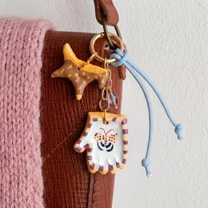 Detail of hand-painted star and glove bag charm with butterfly pattern on a leather bag