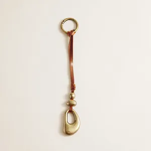 Antique bronze pendant detail with brown leather strap and irregular hollow metal charm