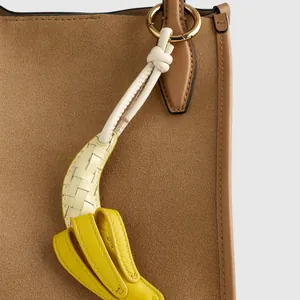 Close-up of a retro leather banana bag charm with white braided detail and gold ring.