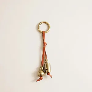 Detailed macro shot of vintage brass bell and bead on a high-quality leather strap keychain