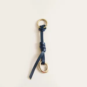 Close-up of vintage navy leather bag charm with distressed brass metallic rings