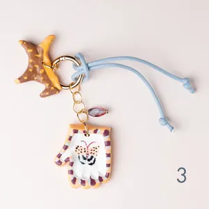 Close-up of hand-painted star and glove bag charm with butterfly pattern