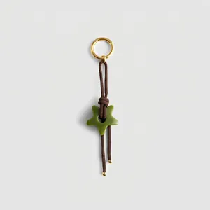Detail of vintage braided cord keychain with green star charm and golden ring