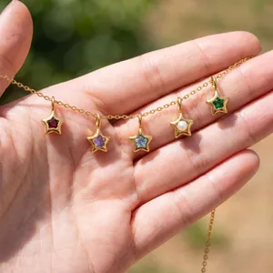 Gros plan d'un collier en acier inoxydable avec cinq pendentifs étoiles en pierres colorées.