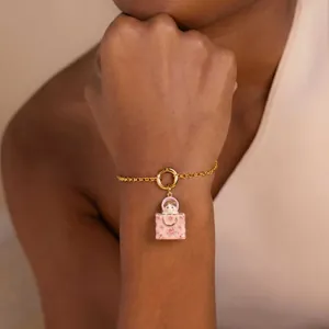 Détail du bracelet chaîne dorée avec charm sac à main fleuri rose et poupée