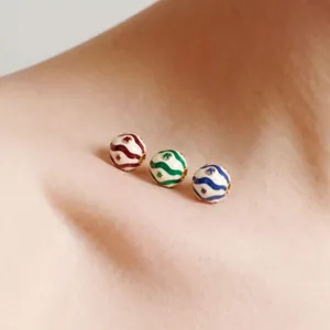 Macro view of three colorful wavy enamel birthstone beads resting on soft skin surface