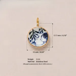 Close-up of round stainless steel pendant with blue fish pattern and gold rim
