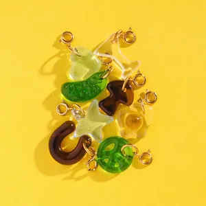 Detail view of colorful resin pendants with gold stainless steel clasps on yellow background