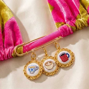 Gedetailleerd overzicht van een gouden veiligheidsspeld met kopjes op roze fluwelen stof
