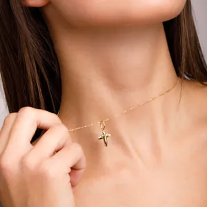 Detail shot of a gold-plated stainless steel airplane pendant necklace on a model.