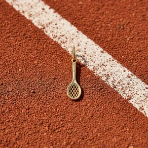 Detail view of 18K gold-plated stainless steel tennis racket pendant on clay court