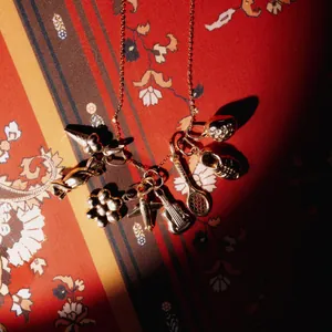 Close-up detail of vintage style gold charms on a patterned background with dramatic shadows