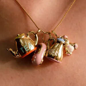 Macro view of 18K gold plated charms featuring a teapot, milk jug, shoe and bear