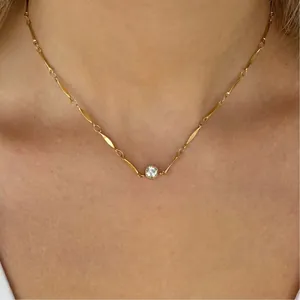 Detalle de un collar minimalista de eslabones de bambú dorado con colgante de cristal