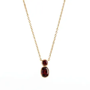 Close-up of minimalist gourd-shaped necklace with two red gemstones in gold bezel setting