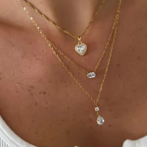 Primer plano de collares dorados en capas con colgantes de cristal en forma de corazón