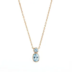Close-up detail of minimalist gold necklace featuring double light blue oval gemstones