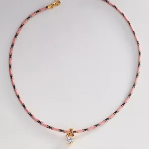 Detailansicht einer rosa Kordelkette mit funkelndem Zirkon-Anhänger in Goldfassung