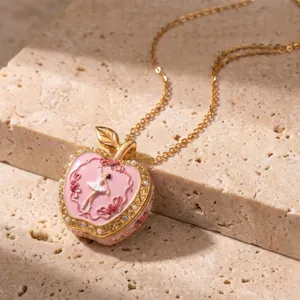 Detailed close-up of a pink enamel apple locket necklace featuring a ballerina relief